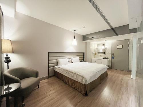 a bedroom with a large bed and a chair at Stay Hotel - Taichung Yizhong in Taichung