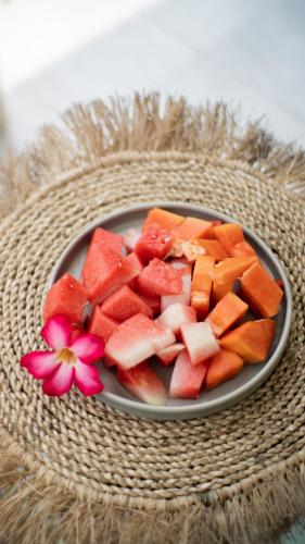 Nucifera Kuta Lombok في كوتا لومبوك: صحن فاكهة على طاولة مع زهرة