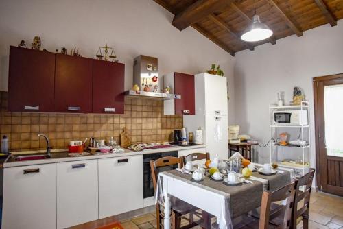 a kitchen with white cabinets and a table with chairs at Villa Farfalla Bianca in Vitorchiano