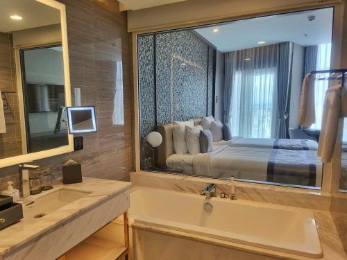a bathroom with a large mirror over a sink and a bed at Diamond Stars Ben Tre Hotel in Ben Tre