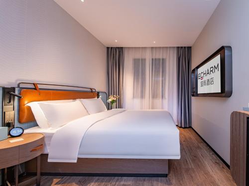 a bedroom with a large white bed and a tv at Echarm Hotel Xianning Hot Spring Center Huatan Branch in Wenquanzhen