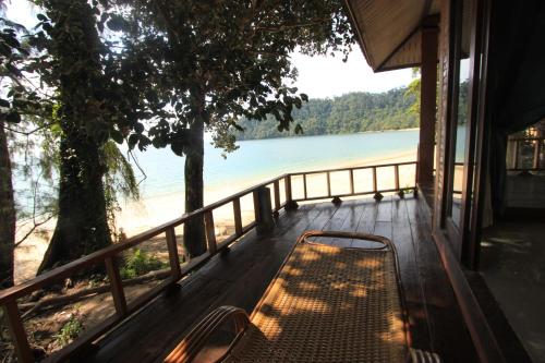 a bench on a porch with a view of a beach at Chomjan Resort in Ko Phayam