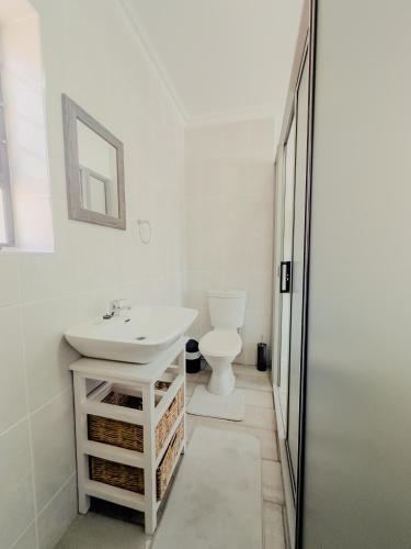 a white bathroom with a sink and a toilet at Gaiaqua Guesthouse in Gqeberha