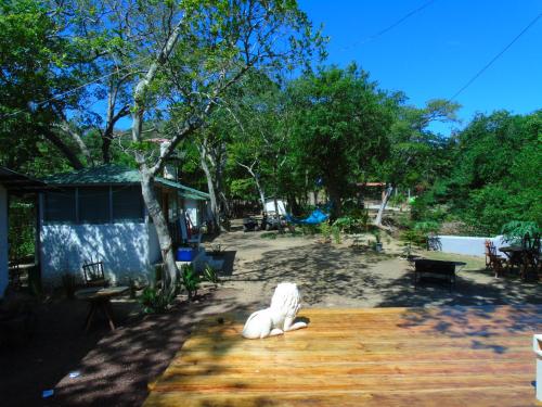 a white dog statue sitting on a wooden deck at Hostal Villas Mexico in San Juan del Sur