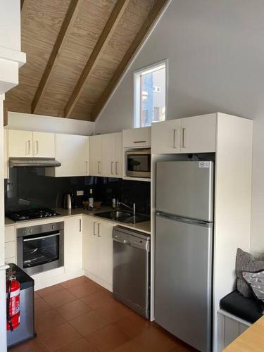 a kitchen with white cabinets and a stainless steel refrigerator at Banjo 3 Chalet - Magnificent view and great location in Thredbo