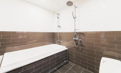 a bathroom with a bath tub and brown tiles at Hotel Browndot Myeongseo Convention in Changwon