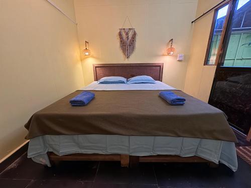 a large bed with two blue pillows on it at Talpona Beach Studios in Canacona