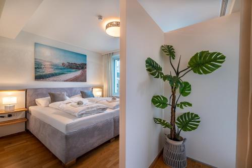 a bedroom with a bed and a potted plant at Well-Home Apartments Velden in Velden am Wörthersee