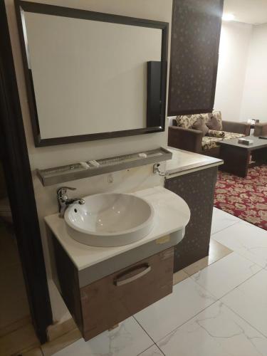 a bathroom with a sink and a large mirror at زيفل للشقق المخدومة in Buraydah