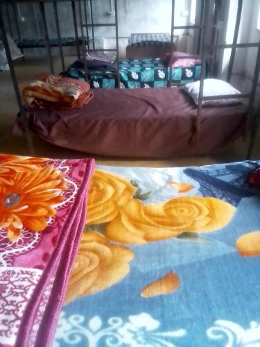 a bed with a blanket and a table with a flower on it at Himalayan Mountain View, Triund Trekking Hostel in Dharamshala