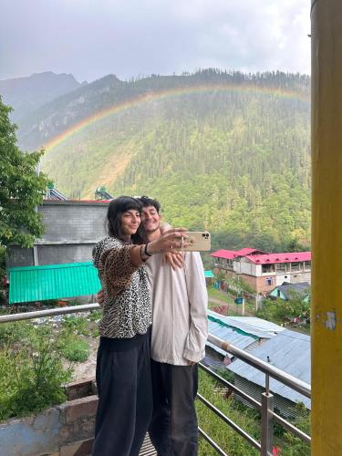 a man and woman taking a picture of a rainbow at Hotel 19 Tosh in Tosh