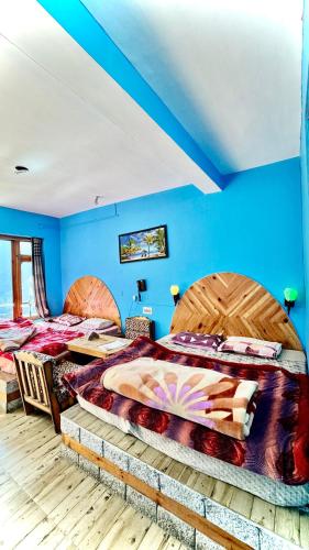 two beds in a room with blue walls at Hotel 19 Tosh in Tosh