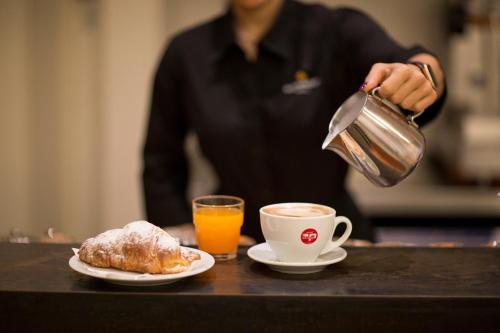 a person pouring a cup of coffee and a plate of food at Blu Arena Hotel in Montecchio