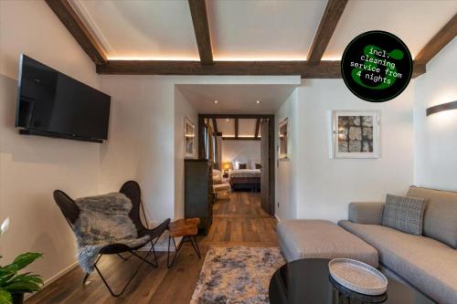 a living room with a couch and a tv at SCHLOSS Zermatt - CBD & Adaptogenic Spa and Sport Hotel in Zermatt