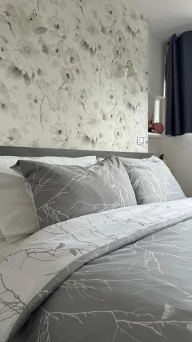 a bed with a gray comforter and a floral wall at Attico Stella Alpina in Terminillo
