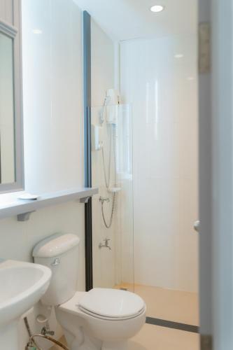 a white bathroom with a toilet and a shower at Apo Hotel in Krabi town
