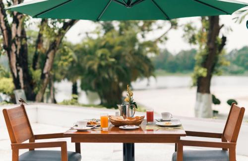 a wooden table with a bowl of food and an umbrella at Inya Lake Hotel Yangon in Yangon
