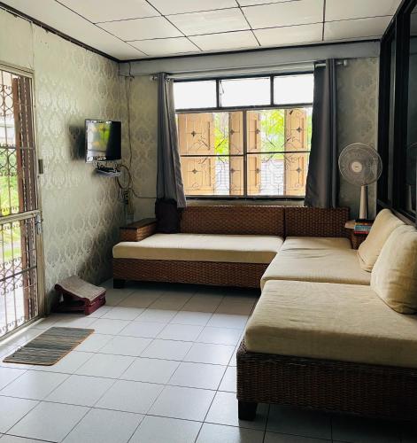 a living room with two beds and two windows at บ้านคุณยายอยุธยา in Phra Nakhon Si Ayutthaya