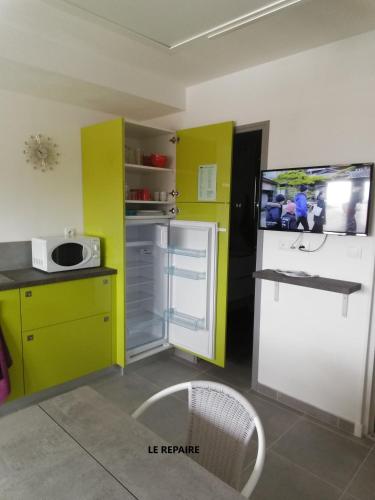 une cuisine avec des armoires jaunes et blanches et un réfrigérateur blanc dans l'établissement Le Repaire, à Cormaranche-en-Bugey