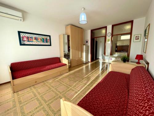 a living room with two red couches and a table at Cozy studio with balcony-Beahost in Porto Santa Margherita di Caorle