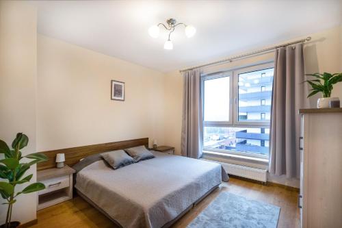 een slaapkamer met een bed en een groot raam bij Cosmo Apartments in Gdańsk