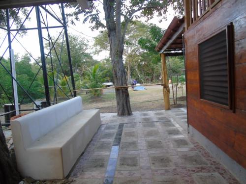 a white couch sitting on a patio next to a tree at Hostal Villas Mexico in San Juan del Sur