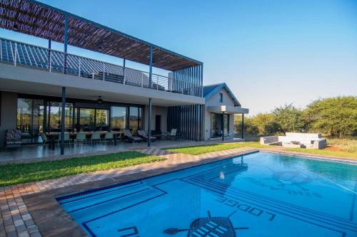 a swimming pool in the backyard of a house at Sihlangu Lodge in Marloth Park