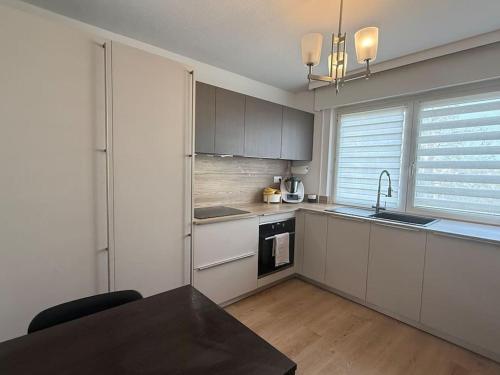 - une cuisine avec des placards blancs et une table noire dans l'établissement Logement lumineux de 92m2, à Colmar