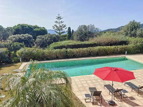un parapluie rouge assis à côté d'une piscine dans l'établissement Villa 13 oliviers Couchers de soleil LUMIO, à Lumio