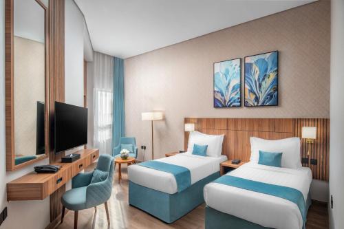 a hotel room with two beds and a television at Elaf Qinwan Hotel in Makkah