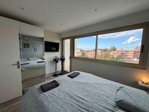 una camera da letto con un letto grande e una grande finestra di Résidence Hermitage 6 pers avec parking a Le Touquet-Paris-Plage