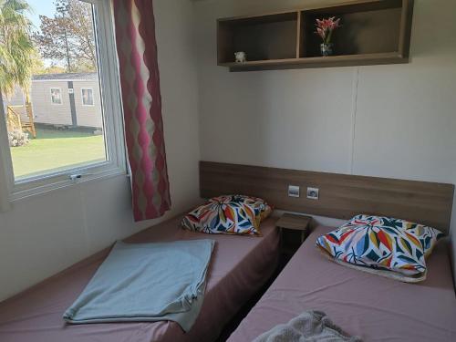 deux lits dans une chambre avec une fenêtre dans l'établissement Mobil home F033 camping la carabasse 4 étoiles Vias, à Vias