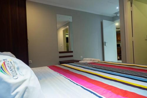 a bedroom with a bed with a colorful striped blanket at Ossanzaia Bilene Lodge in Vila Praia Do Bilene