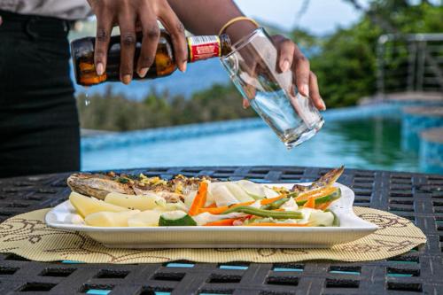 a person holding a bottle of water over a plate of food at Ossanzaia Bilene Lodge in Vila Praia Do Bilene