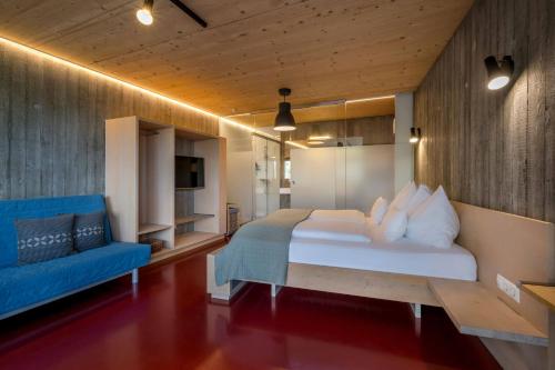 a bedroom with a large bed and a blue couch at WURZENBERG Hotel Lodges Südsteiermark in Gamlitz