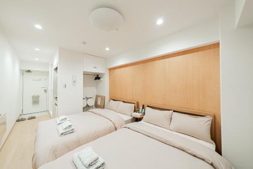 two beds in a hotel room with white sheets at Kiwami Hotel Shinjuku in Tokyo