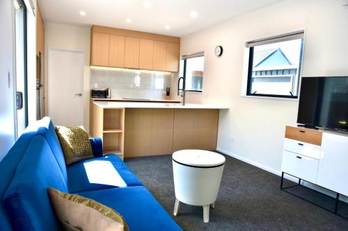 a living room with a blue couch and a kitchen at Groups Wanted Stylish 3BR City Pad 3 Baths Onsite Garage in Christchurch