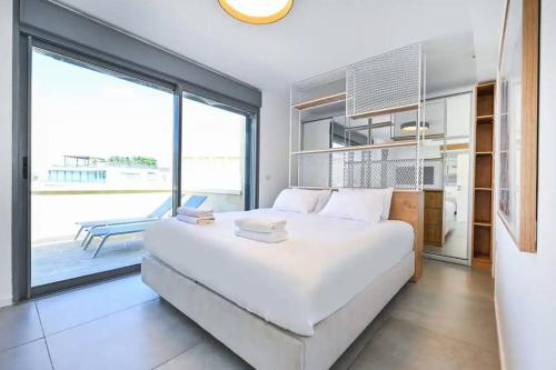 a bedroom with a large white bed and a large window at Ben Yehuda Dream Penthouse in Tel Aviv