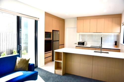 a kitchen with a counter and a blue couch in a room at Groups Wanted Stylish 3BR City Pad 3 Baths Onsite Garage in Christchurch