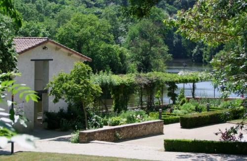 un jardin avec un bâtiment et une bande de plantes dans l'établissement Appartement au bord de la Sèvre Nantaise, à La Haie-Fouassière