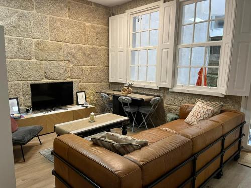 a living room with a brown leather couch and a tv at House Pajarillo in Vigo