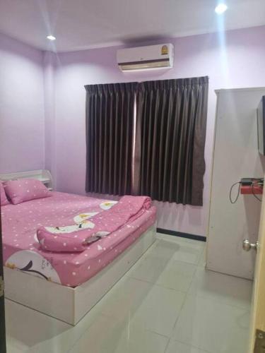 a bedroom with a pink bed and a window at ThawornSuk Pool Villa in Cha Am
