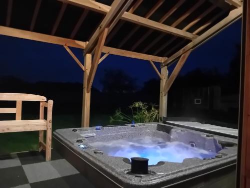 un bain à remous sur une terrasse avec une chaise en bois dans l'établissement Gîte Le Bel Air, à Reigny