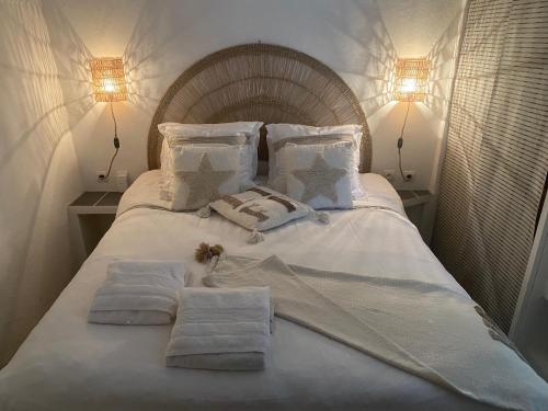 un lit blanc avec des serviettes dessus avec deux lumières dans l'établissement Flora, à Les Brousses
