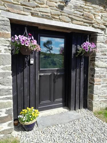 a door of a stone building with two baskets of flowers at The nest in Spézet