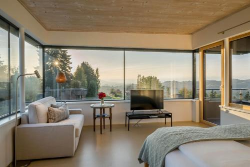 a bedroom with a bed and a tv and large windows at WURZENBERG Hotel Lodges Südsteiermark in Gamlitz
