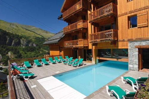 un complexe avec une piscine, des chaises et un bâtiment dans l'établissement Duplex T3, ski aux pieds, plein sud, Piscine, à Valloire