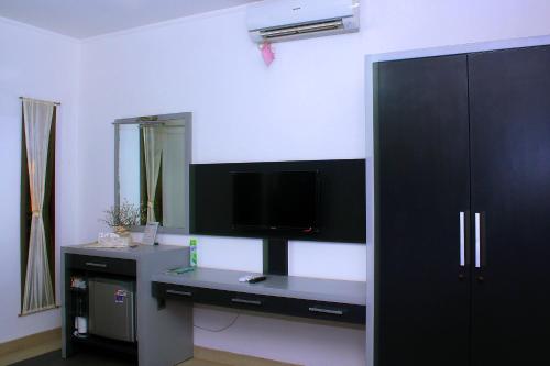 a room with a desk with a tv on a wall at Villa Rumah Putih Abu Abu in Senggigi 