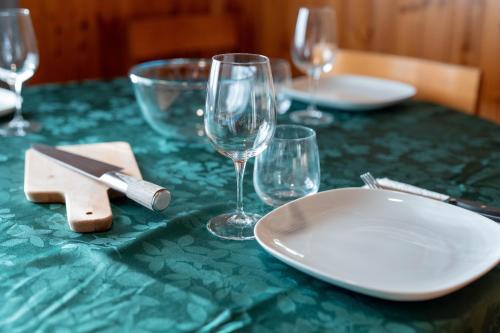 a green table with plates and wine glasses on it at 5 minuti da Asiago - Garage e BBQ in Roana