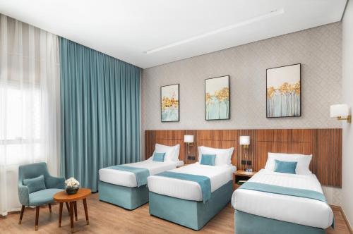 a hotel room with two beds and a chair at Elaf Qinwan Hotel in Makkah